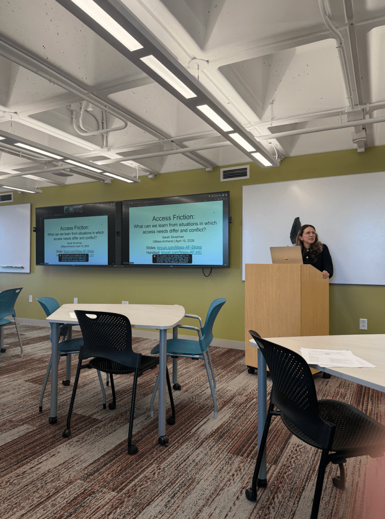 Sarah Silverman speaking in front of podium. Text visible behind on screen reads "access friction"